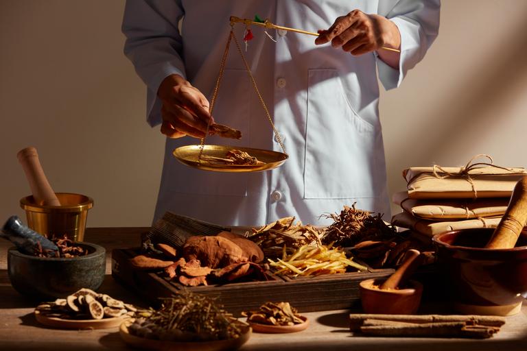 Traditionelle chinesische Medizin mit Kräutern und Gewürzen in braunen hölzernen Hintergrund und ein Arzt