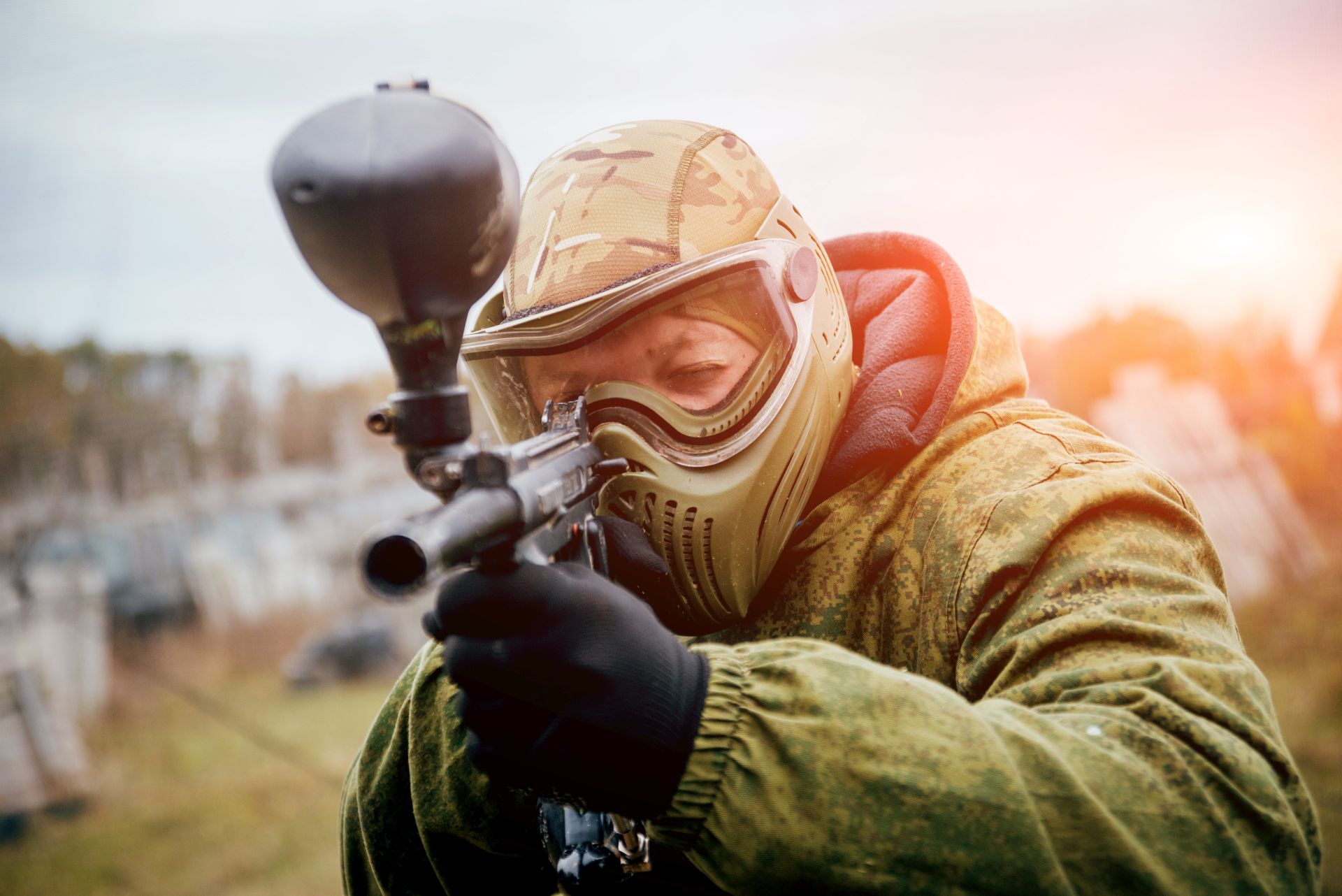 Spieler mit Paintball Helm und Maske zielt während eines Matches, mit optimaler Schutzausrüstung für Sicherheit und Komfort.