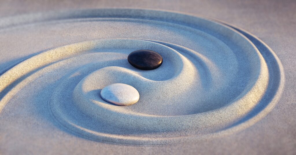 Yin-Yang mit Steinen im Sand | Betreuungskraft Weiterbildung